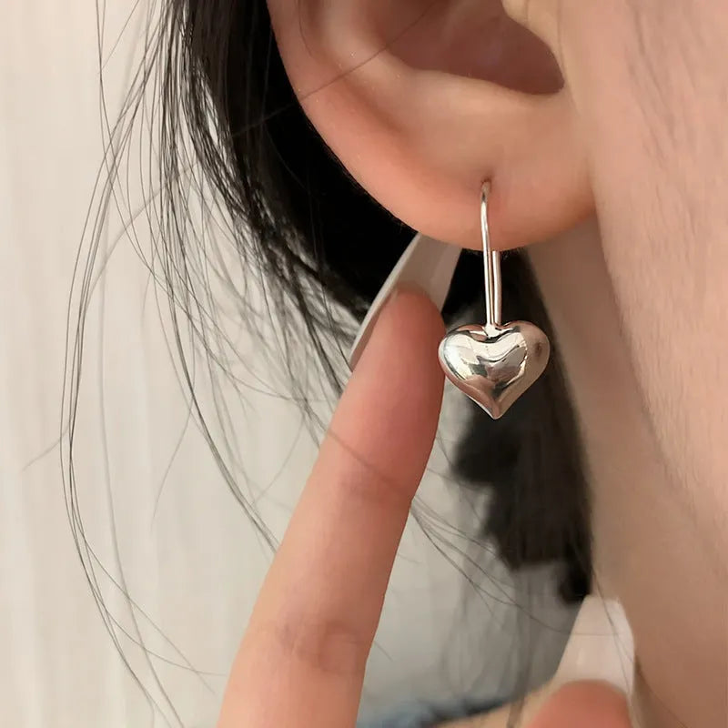 Silver-coloured heart-shaped earrings with three-dimensional glossy design and Korean-style aesthetic