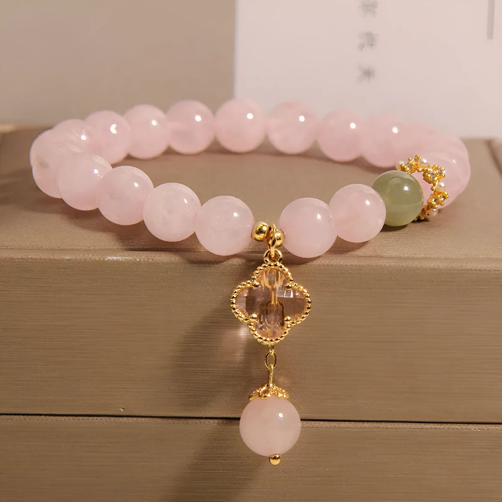 Pink crystal four-leaf clover pendant bracelet for women with rhinestones on alloy band.