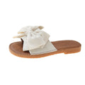 Women's beige suede slip-on sandals with bow detail and flat rubber sole