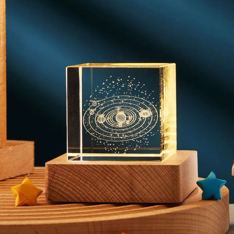 Transparent glass cube night lamp projecting a warm nebula light pattern on a desk.