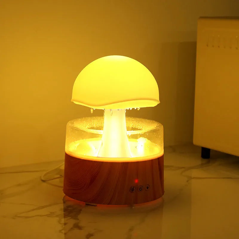 White cloud-shaped humidifier with raindrop simulation and colour-changing lights on wooden surface