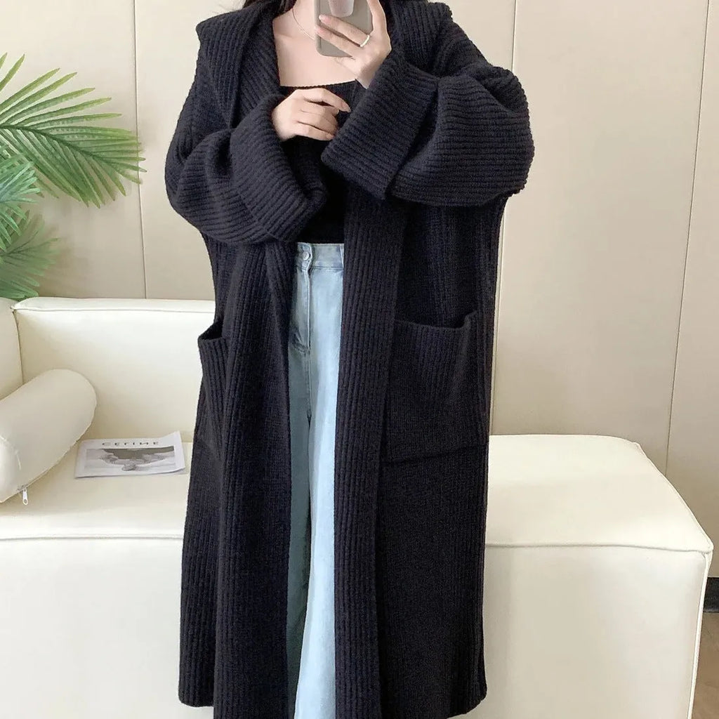 Loose grey hooded sweatshirt cardigan coat with raglan sleeves on a hanger.