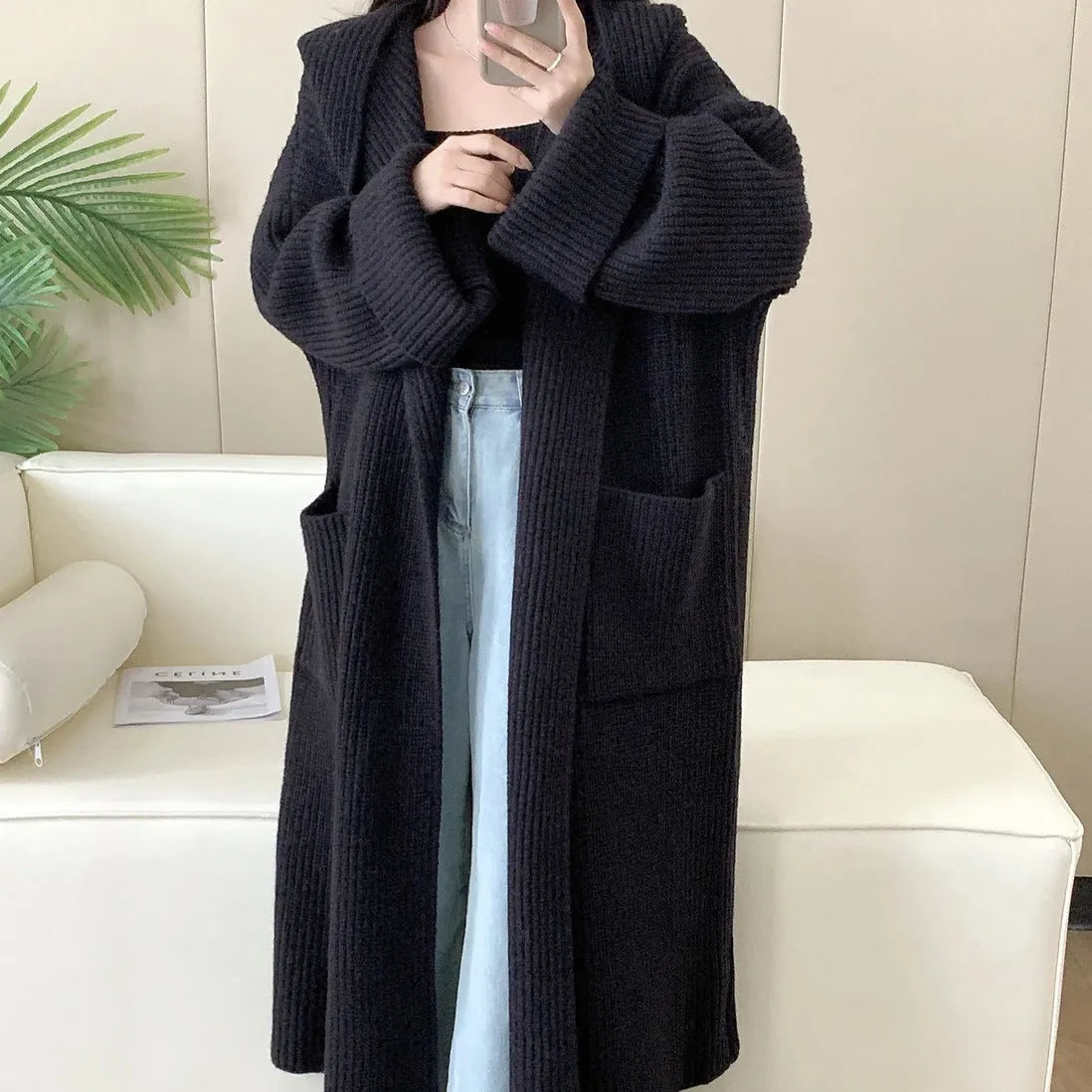 Loose grey hooded sweatshirt cardigan coat with raglan sleeves on a hanger.