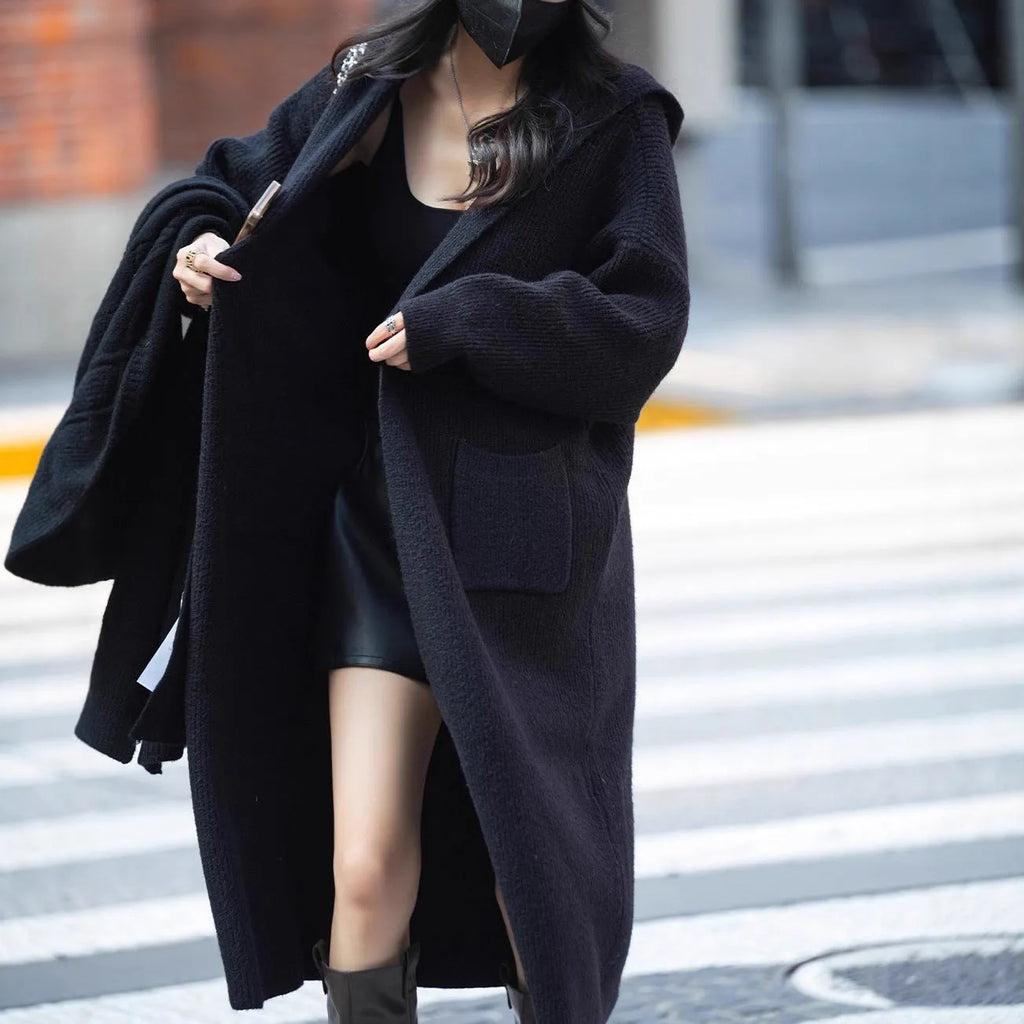 Long grey knitted hooded trench coat cardigan on a hanger, showing loose fit and long sleeves.