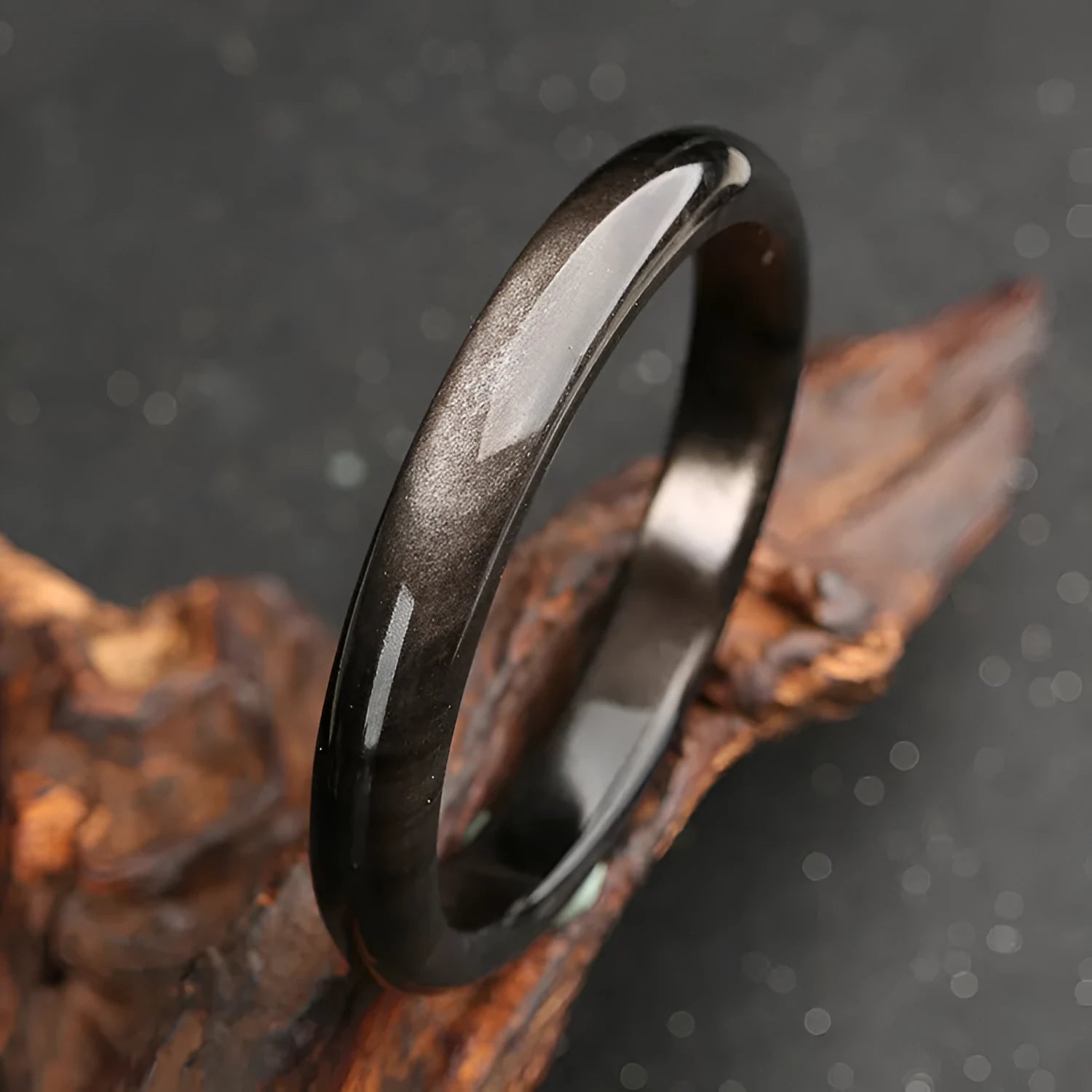 Ethnic geometric obsidian cat's eye bracelet in silver stone colours on a wrist.