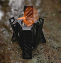 Black foldable hexagon alcohol stove for camping shown next to a ruler showing its 15cm height.