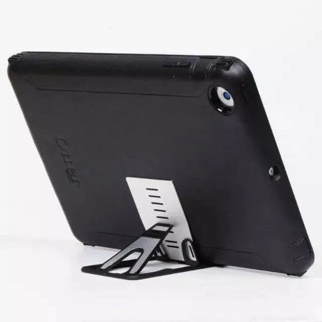 Black card phone holder bracket measuring 8.5cm by 5cm on desktop
