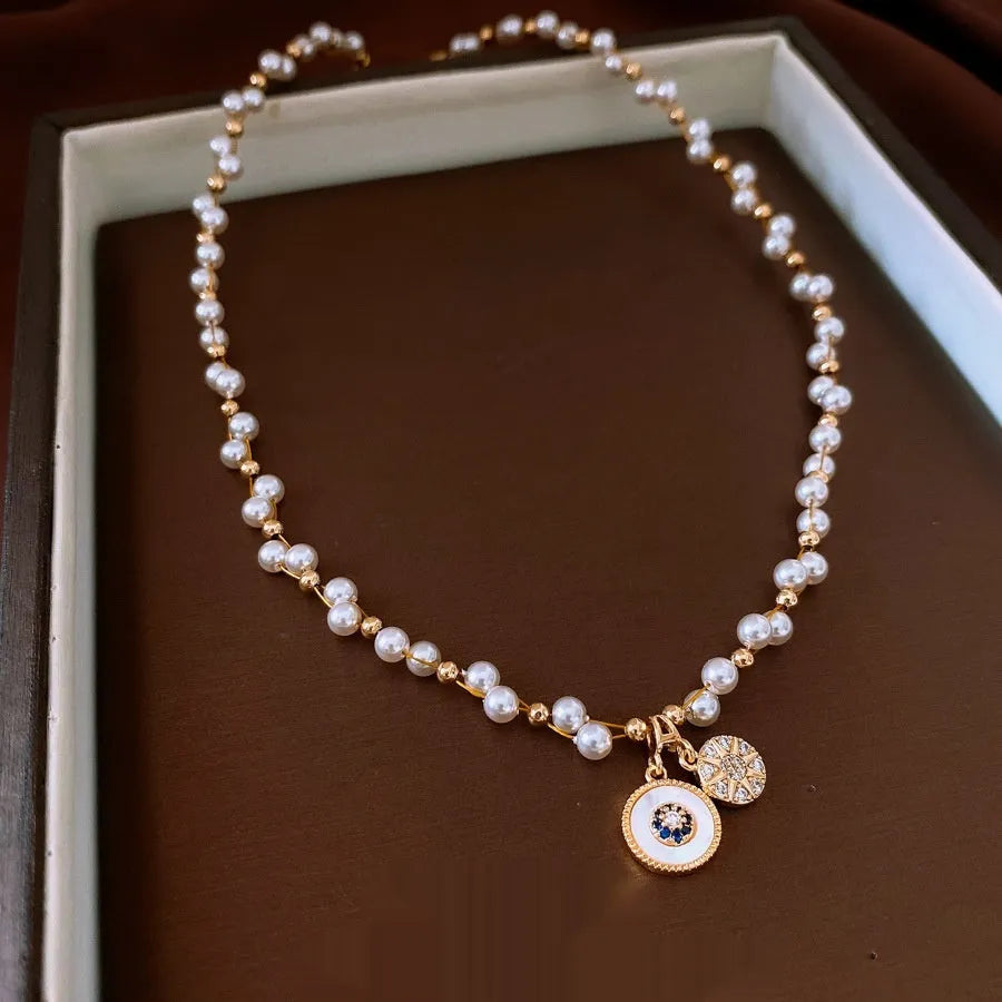 Gold electroplated necklace with round imitation pearl pendant featuring zircon details on adjustable clavicle chain