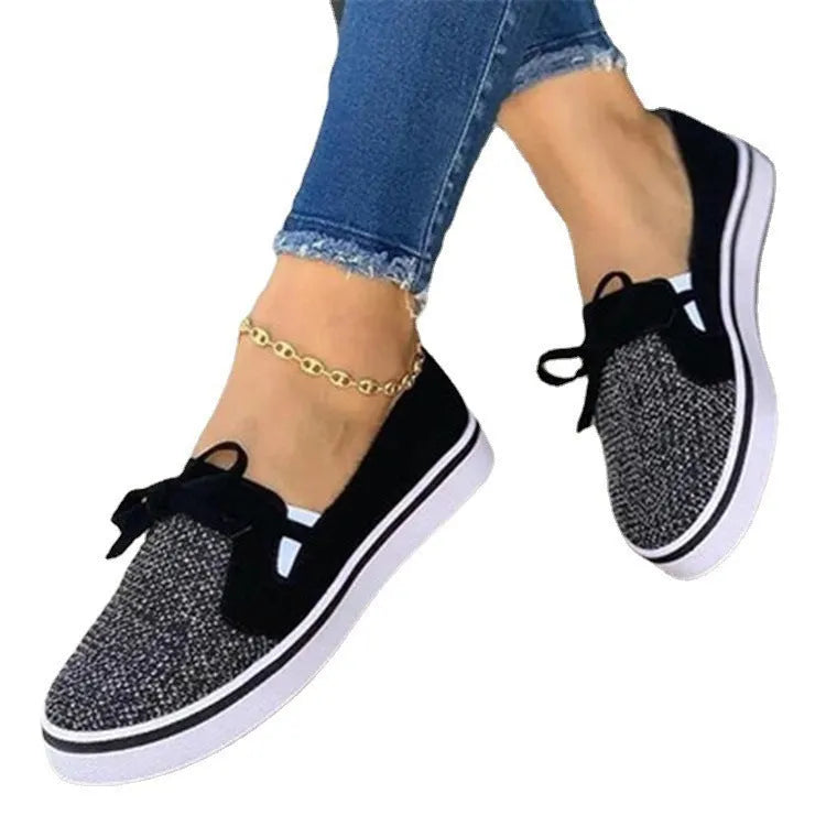 White women's lace-up canvas flat shoes with cross straps and round toe on a plain background