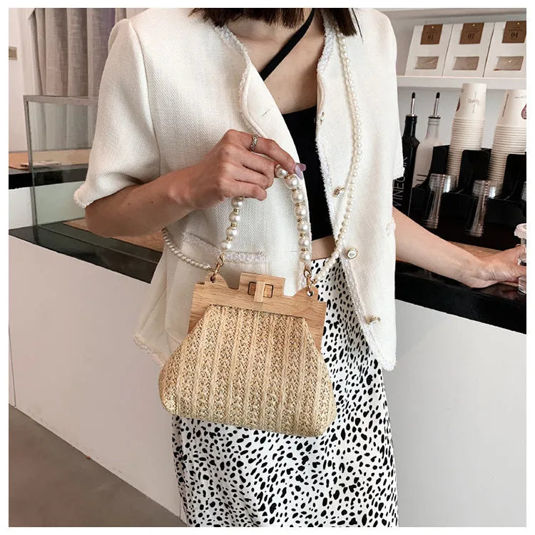Women's woven straw shoulder bag with pearl chain strap showing interior organisation compartments