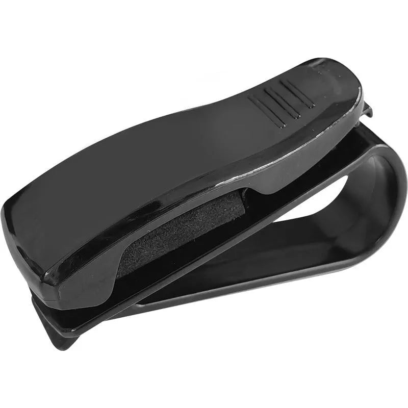 Black plastic clip mounted on a car sun visor holding a pair of sunglasses and an ID card.