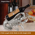 Decorative lobster-shaped wine rack ornament in rose gold or silver resin and plastic on a tabletop.