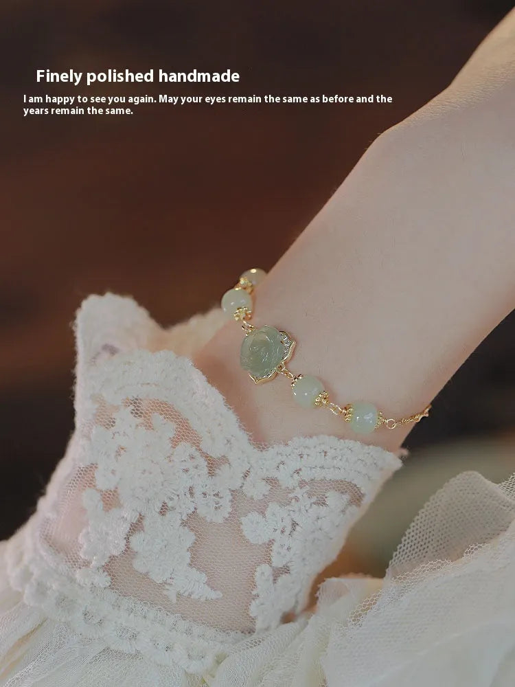 Close-up of a women's Hetian Jade bracelet with rose design and 14K gold gilding.