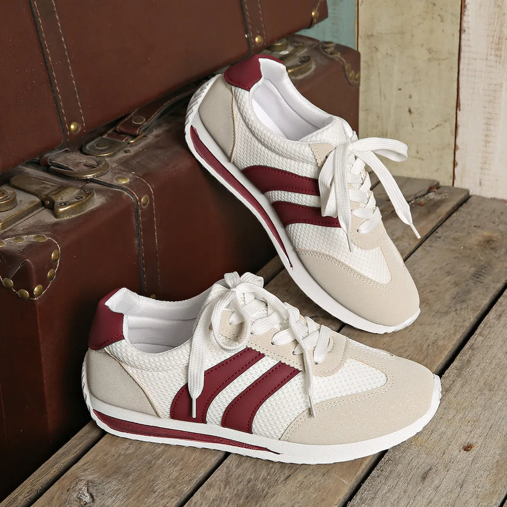 Wine red women's low-top sneaker with mesh upper, synthetic leather accents, and elastic cross straps on a flat rubber sole.