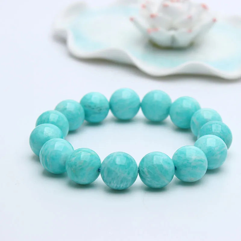 A single green amazonite bead bracelet on an elastic cord, shown in a natural setting.