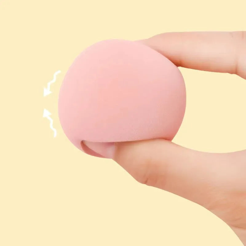 Set of seven differently shaped coloured makeup sponges including pear, heart, and drop shapes on a white background.