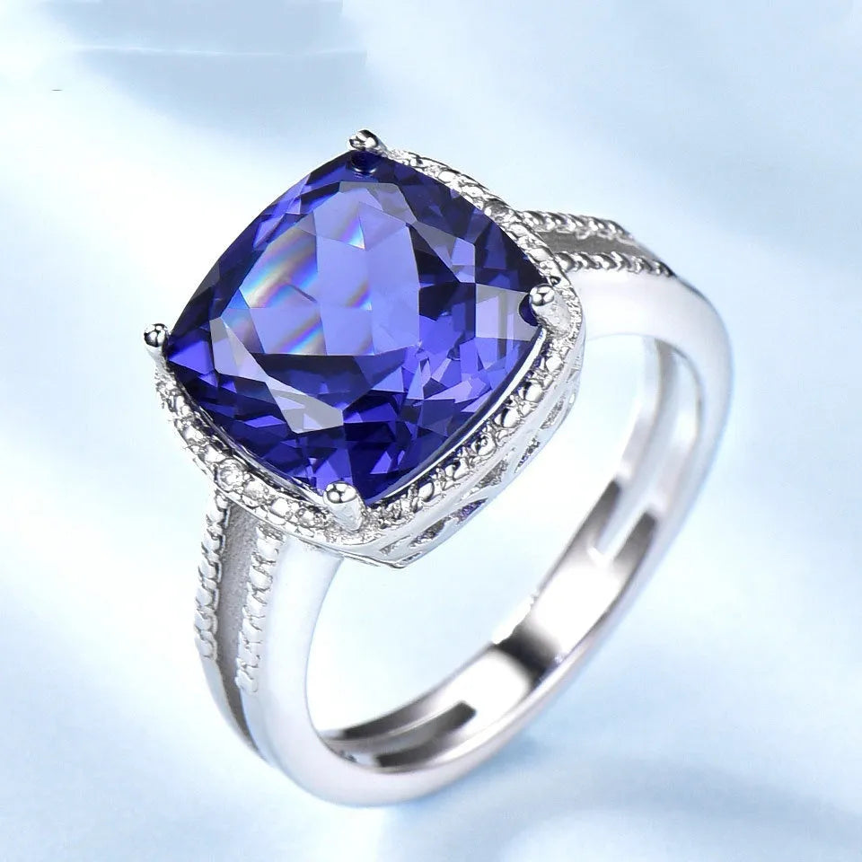 Blue tanzanite stone set in a sterling silver women's ring on a white background.