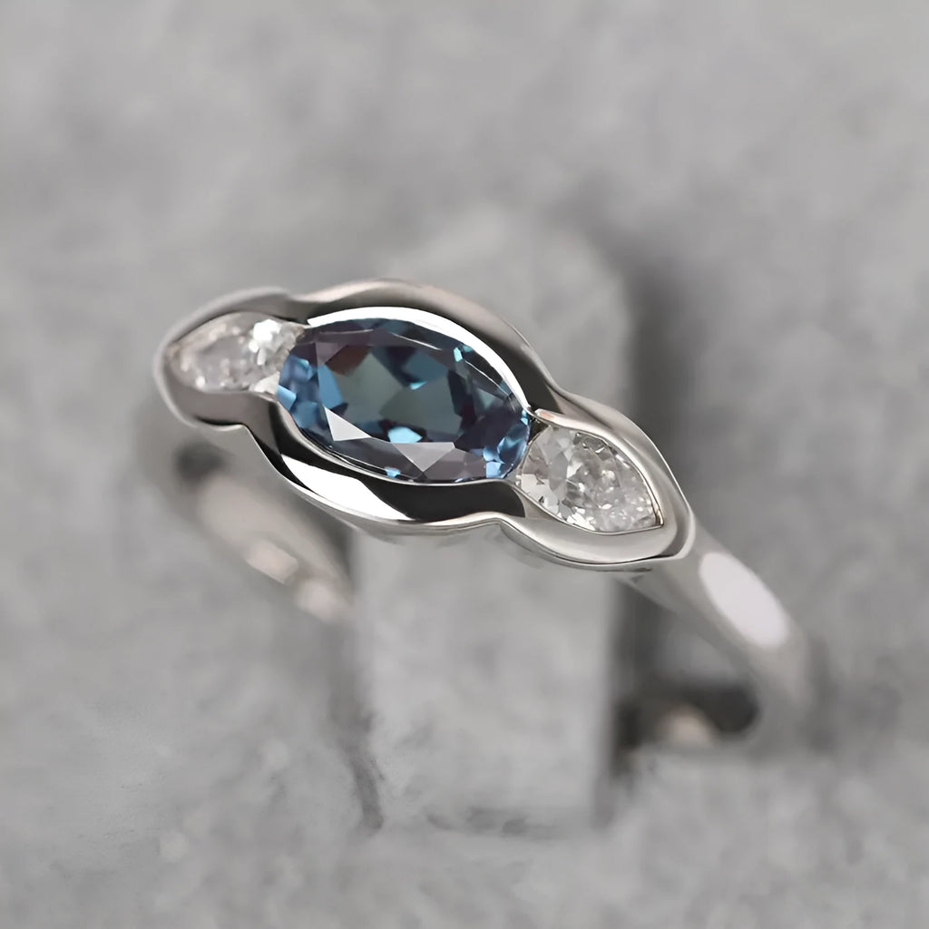Geometric ellipse-shaped ring in white gold colour with zircon inlay, shown on a hand.