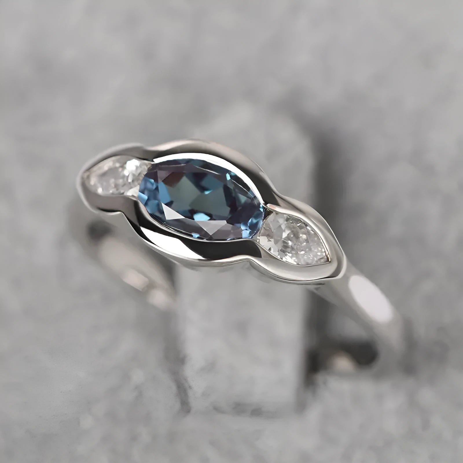 Geometric ellipse-shaped ring in white gold colour with zircon inlay, shown on a hand.
