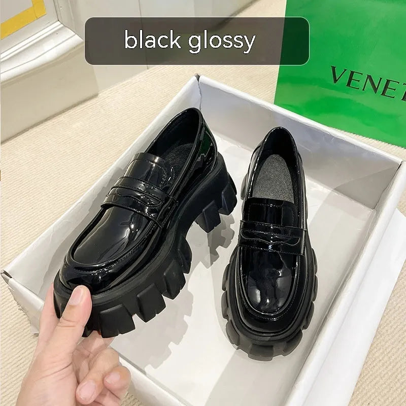 Women's wide fit patent leather loafers with a muffin heel and shallow opening on a rubber sole.