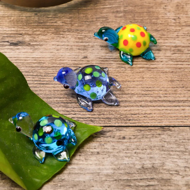 Handmade geometric glass turtle desktop ornament in a multicolour design on a wooden surface.