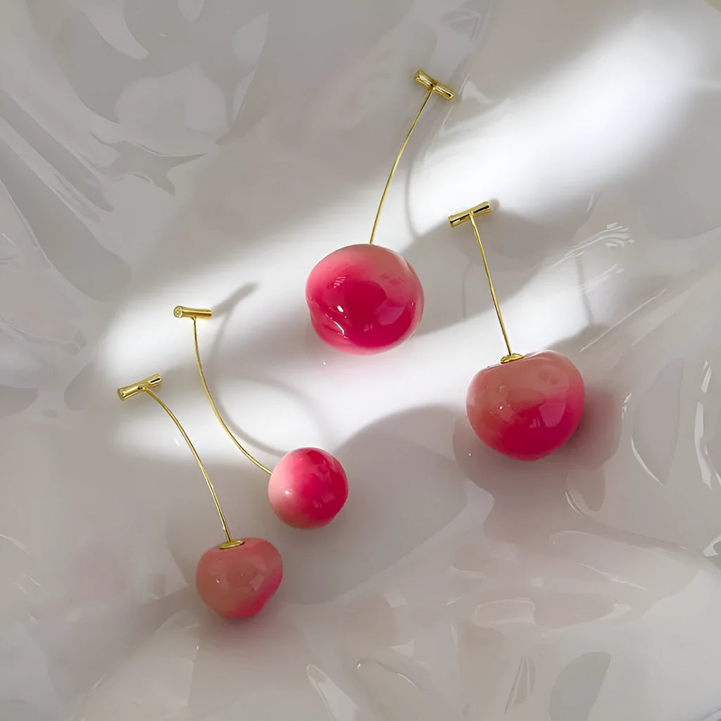 A pair of peach fruit-shaped stud earrings made from red and green acrylic with copper posts.