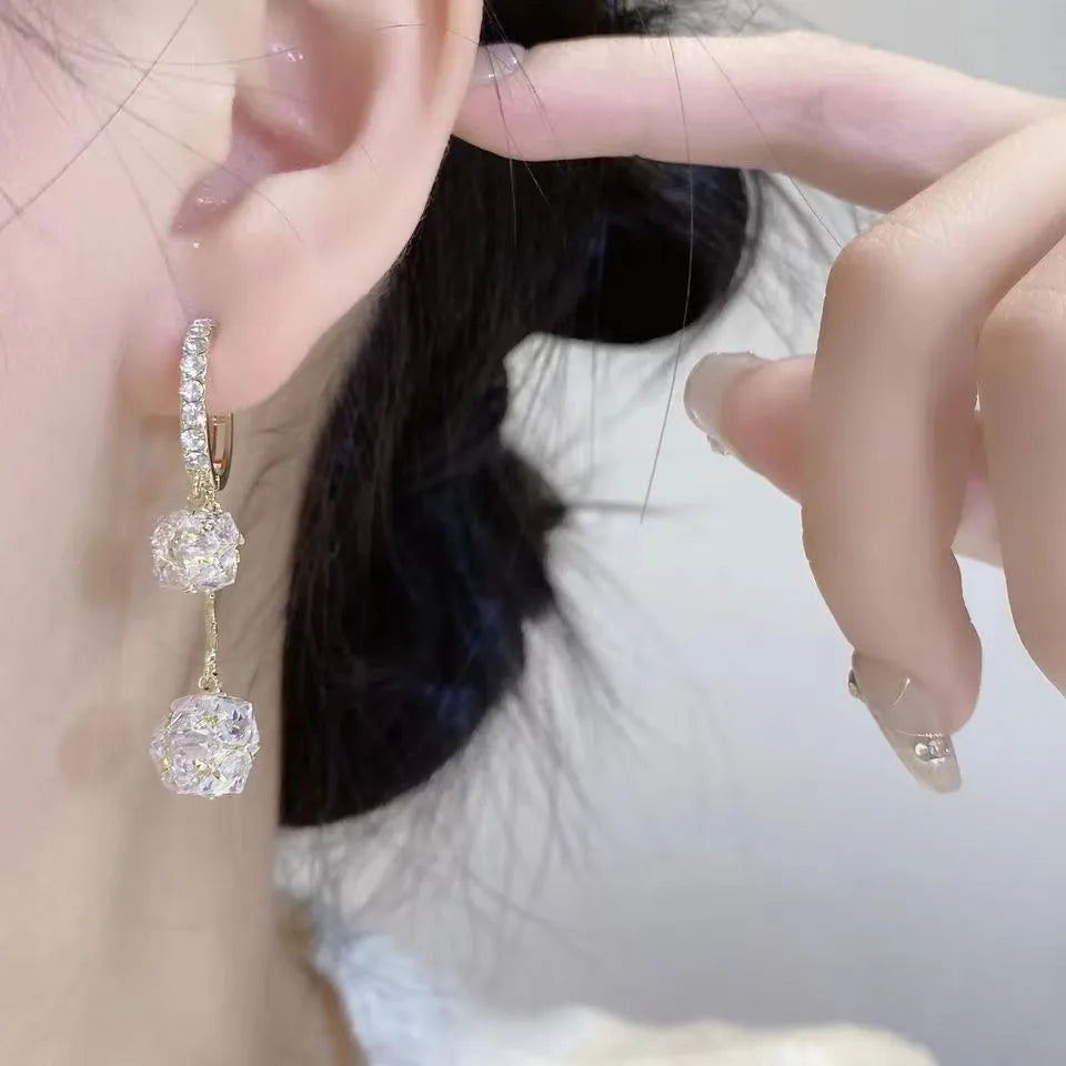 Silver women's clip-on drop earrings with a tassel ball and rhinestone ball pendant.