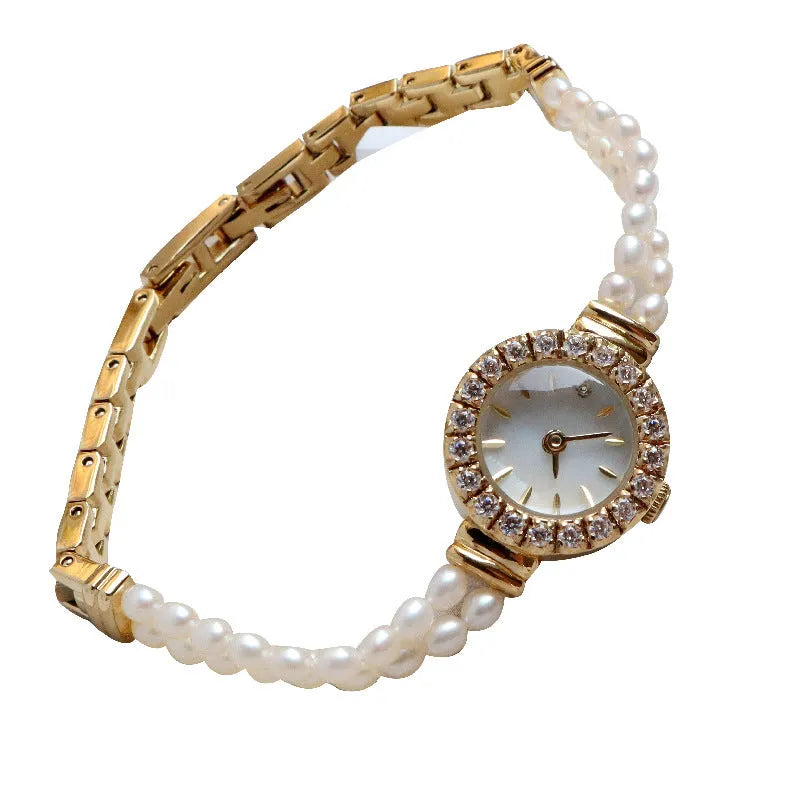 Women's light gold bracelet watch with freshwater pearls and a round 18mm dial on a stainless steel strap.