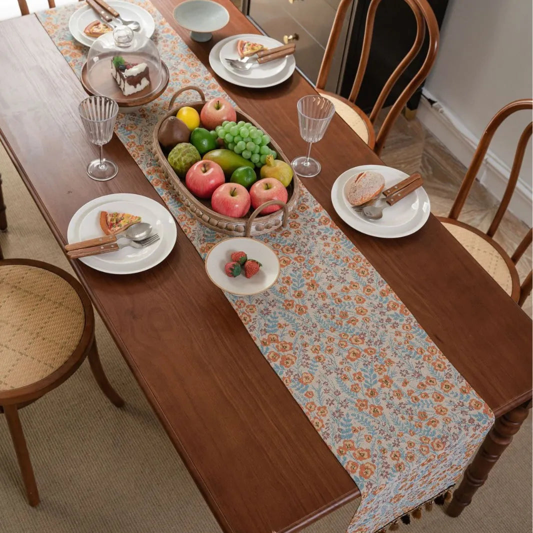 Beige jacquard table runner with long tassels and embroidered floral pattern.