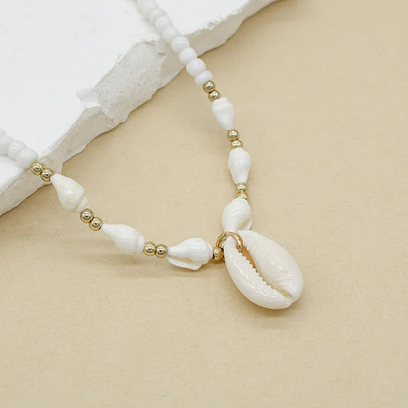 White bead necklace with conch-shaped mother of pearl shellfish pendant and regular chain