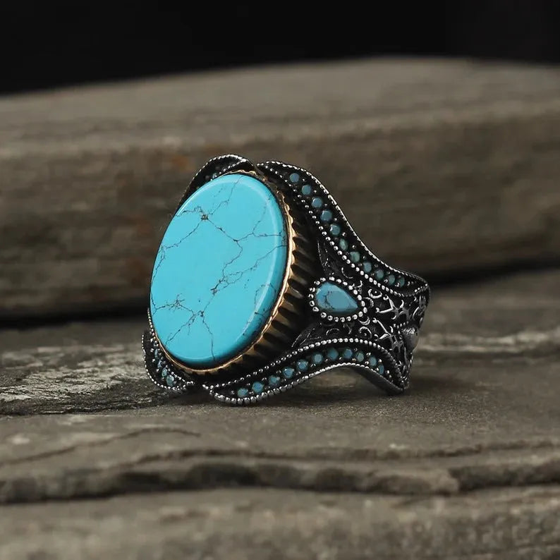Men's antique silver alloy ring with a round turquoise-coloured stone, shown on a hand.