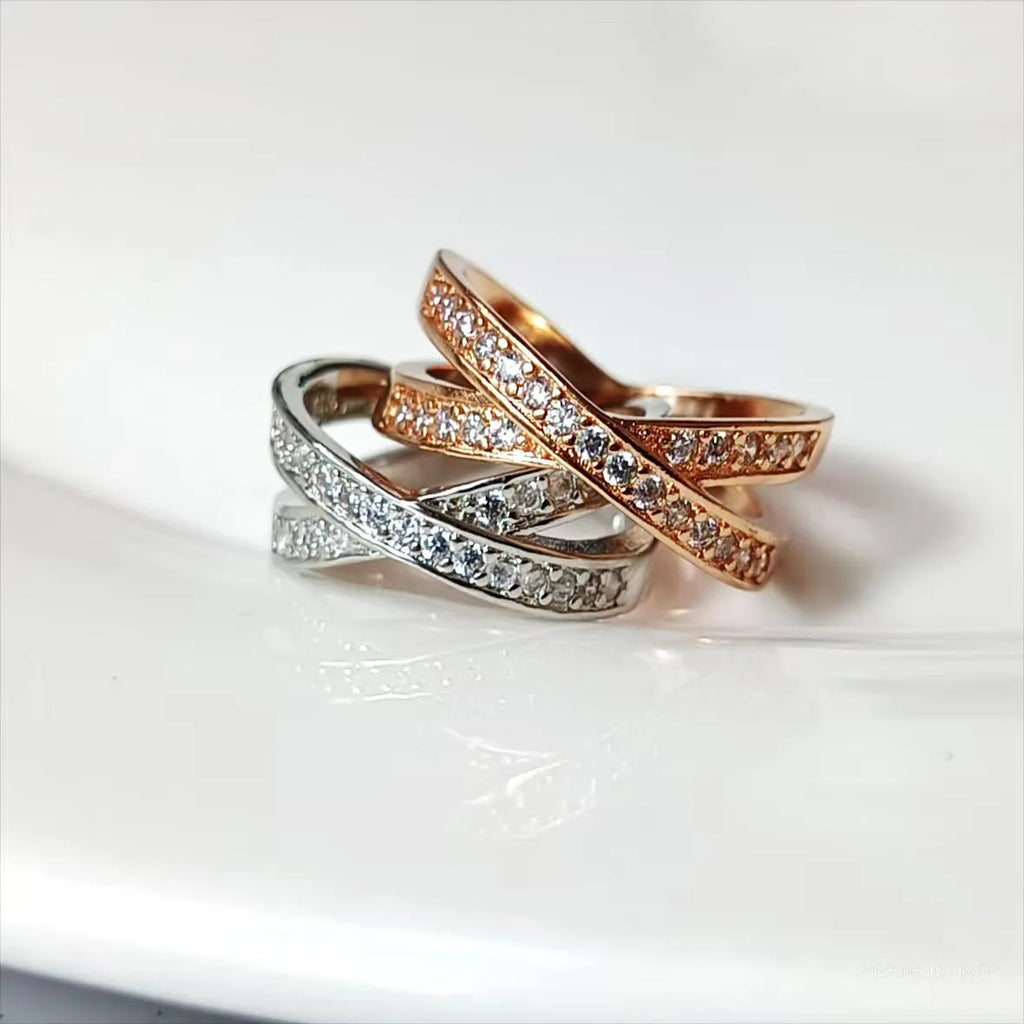 Silver and rose gold metal cross ring with micro-inlaid zircon stones in heart and geometric shapes.
