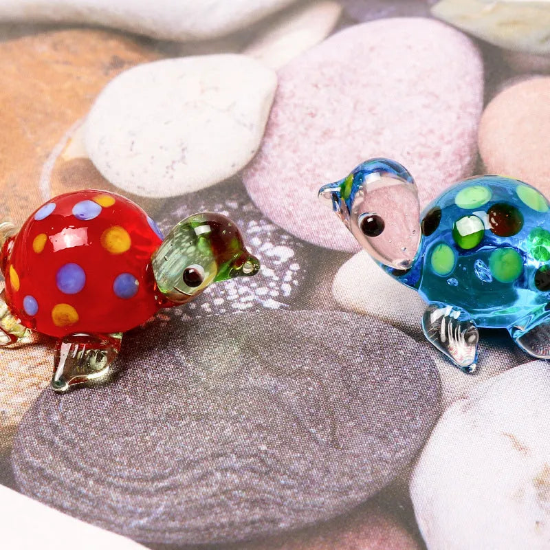 Handmade geometric glass turtle desktop ornament in a multicolour design on a wooden surface.