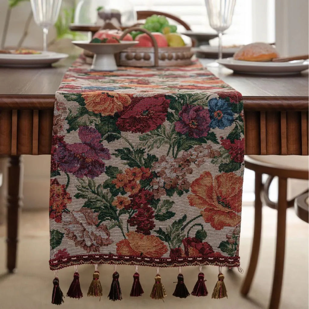 Beige jacquard table runner with long tassels and embroidered floral pattern.