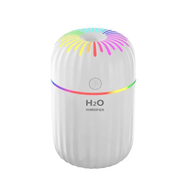 A green USB mini car aromatherapy humidifier on a desk next to a laptop, showing its compact size.