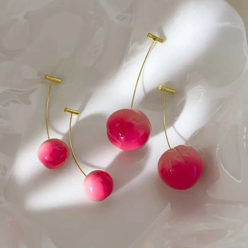 A pair of peach fruit-shaped stud earrings made from red and green acrylic with copper posts.