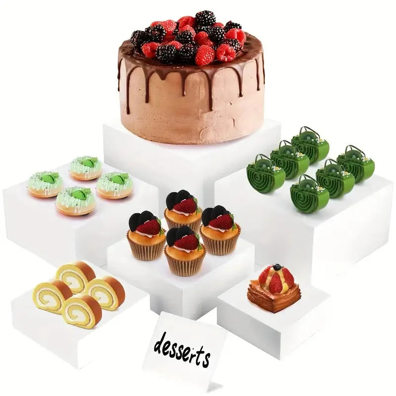 Set of six white plastic cubic dessert display stands in graduated sizes arranged in a row.