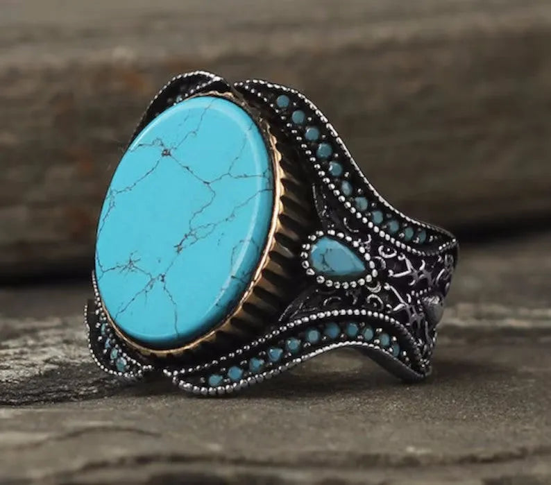 Men's antique silver alloy ring with a round turquoise-coloured stone, shown on a hand.