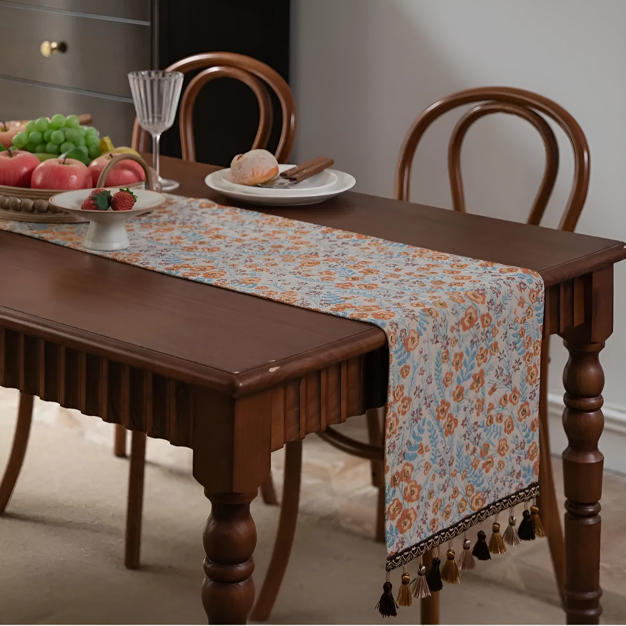 Beige jacquard table runner with long tassels and embroidered floral pattern.