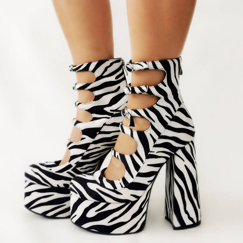 Women's black patent leather platform heel ankle boots with a thick heel and serpentine belt buckle.