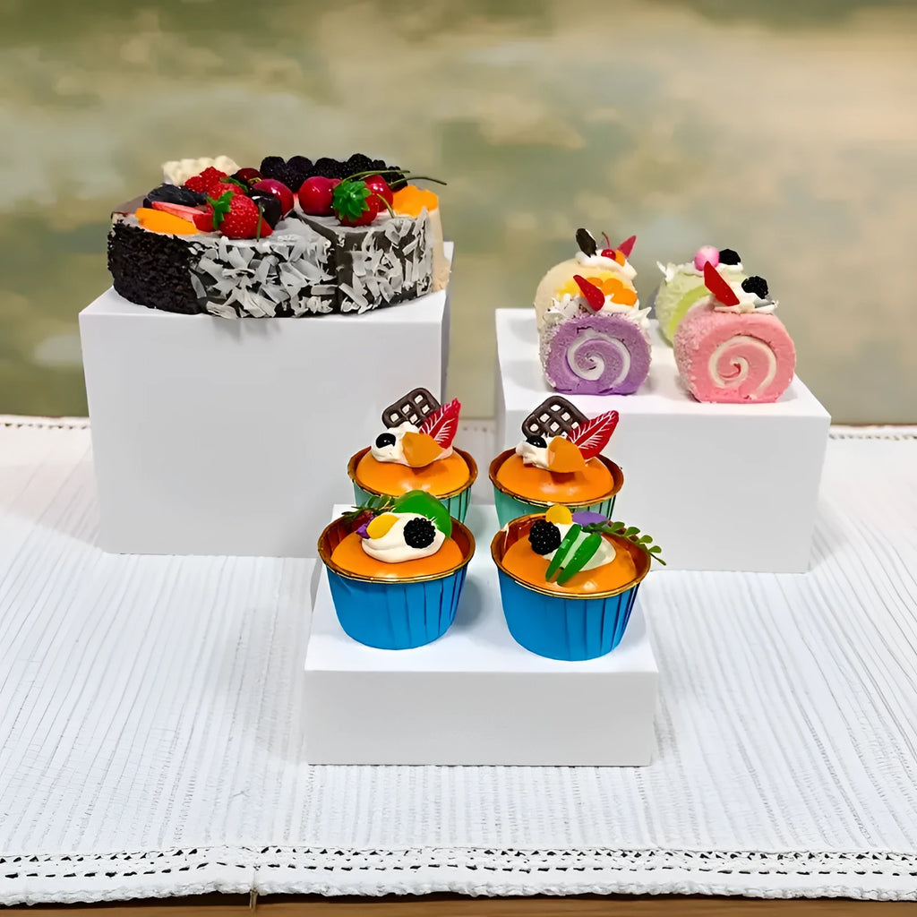 Set of six white plastic cubic dessert display stands in graduated sizes arranged in a row.