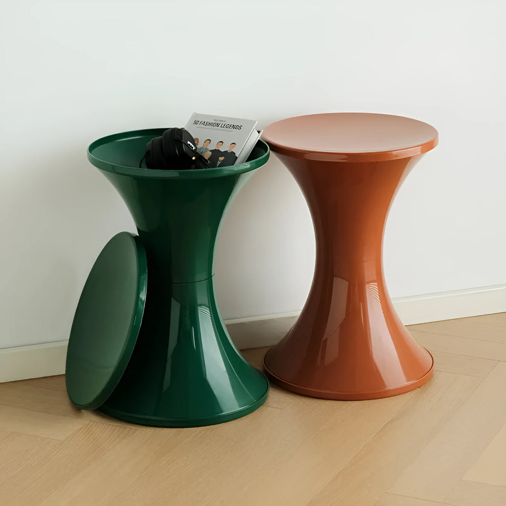 A green plastic hourglass-shaped shoe changing stool on a wooden floor.