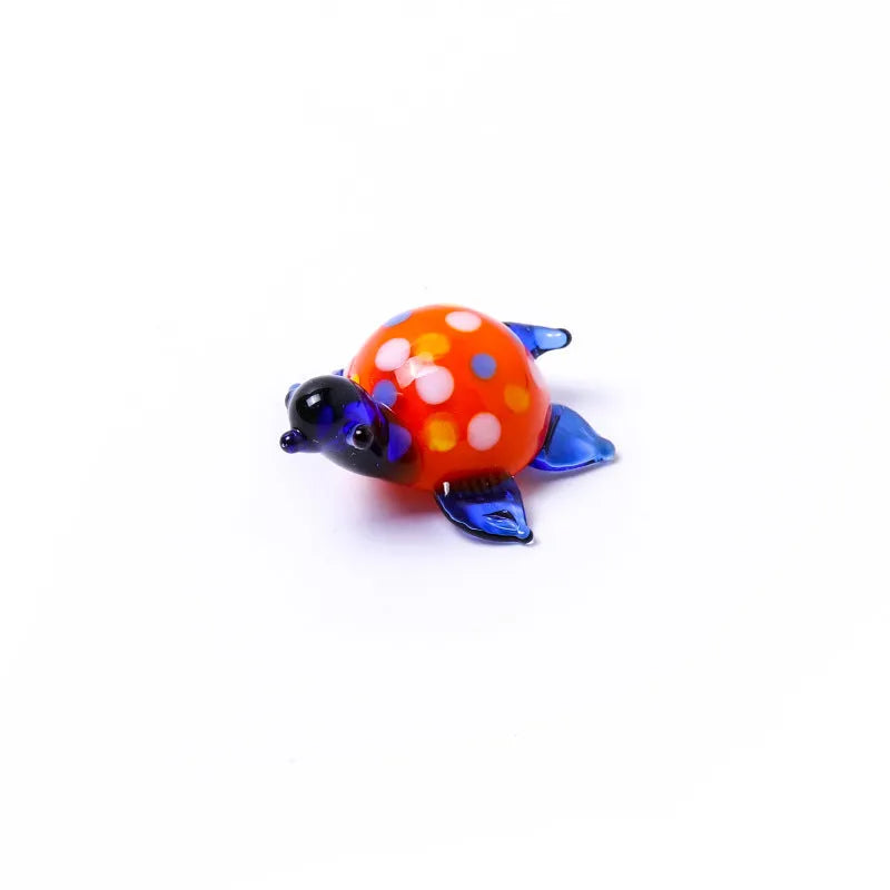 Handmade geometric glass turtle desktop ornament in a multicolour design on a wooden surface.