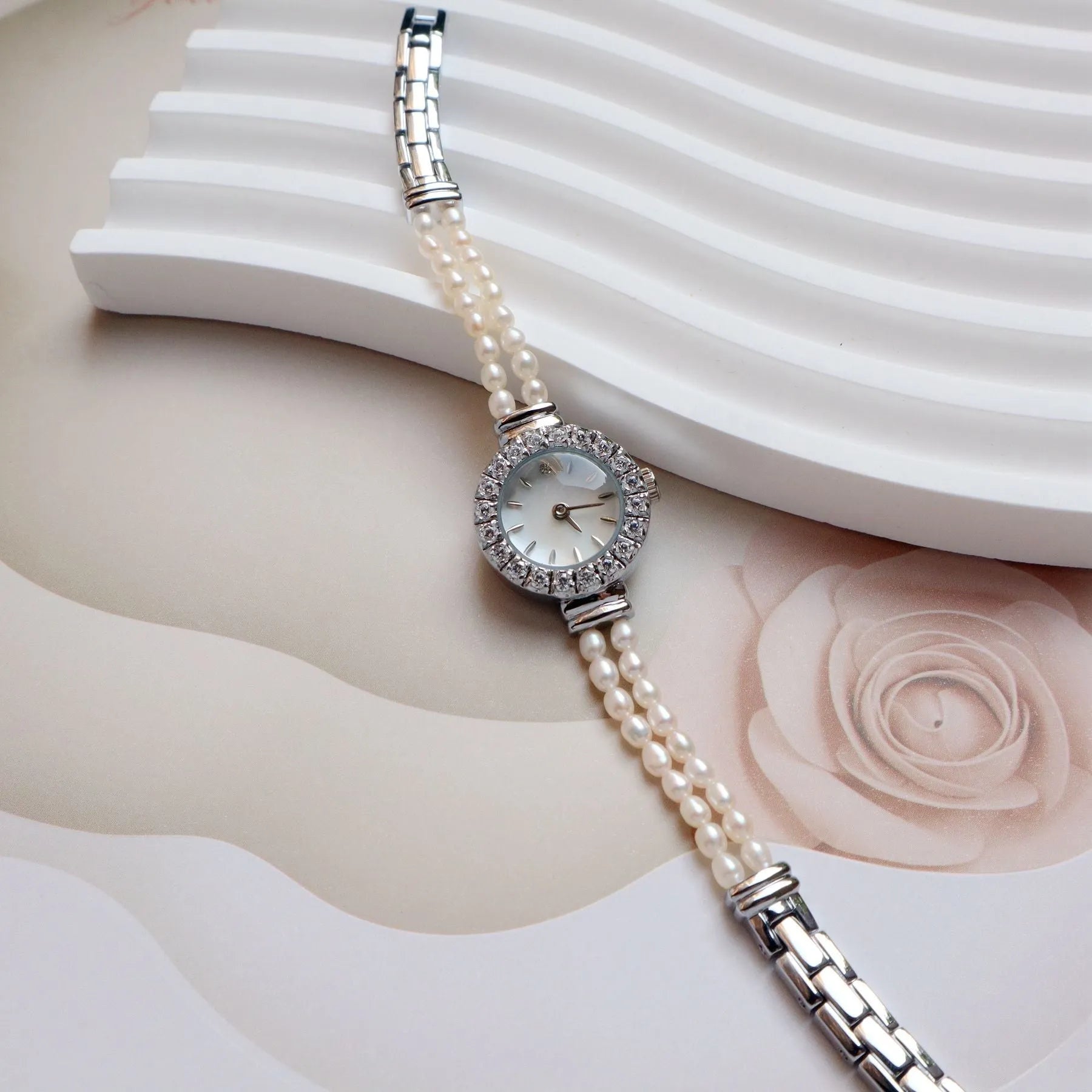 Women's light gold bracelet watch with freshwater pearls and a round 18mm dial on a stainless steel strap.