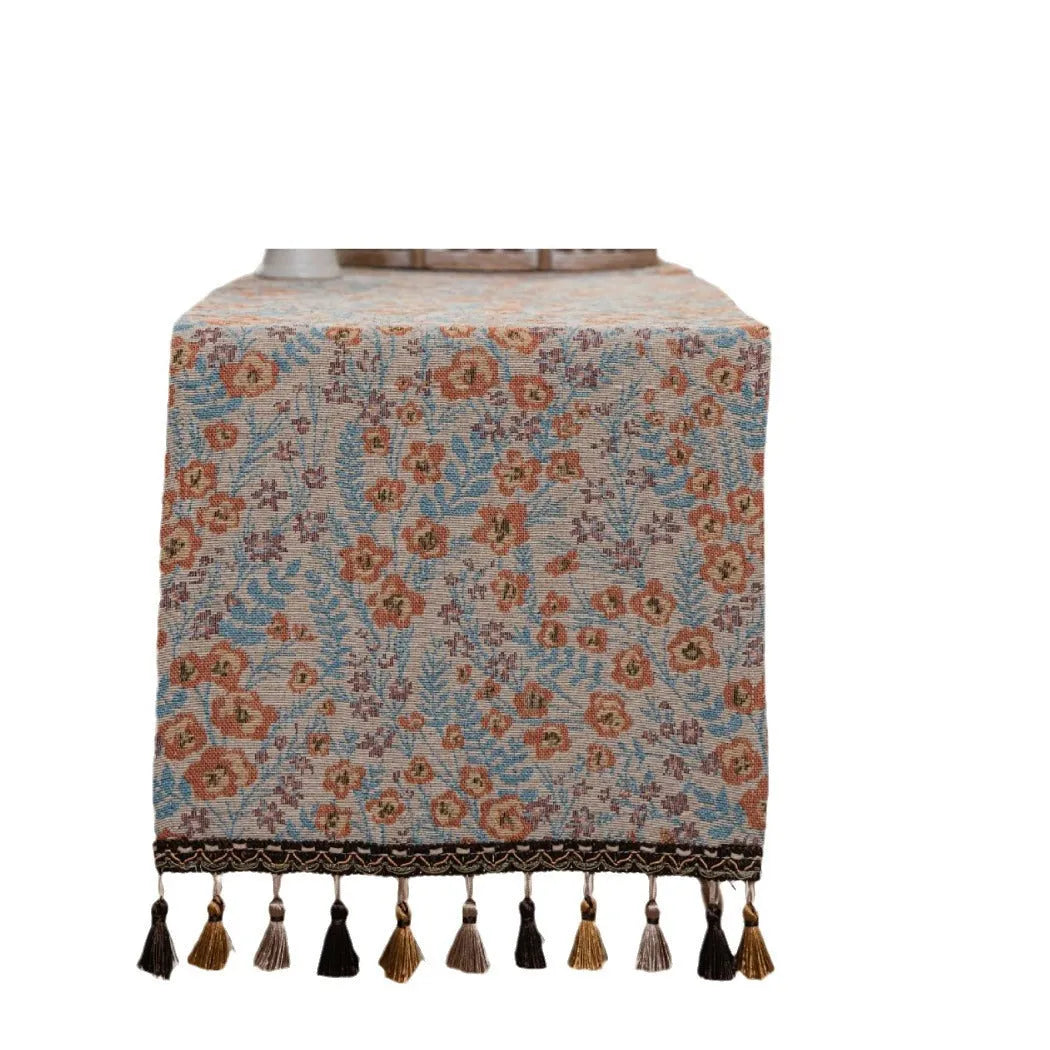 Beige jacquard table runner with long tassels and embroidered floral pattern.