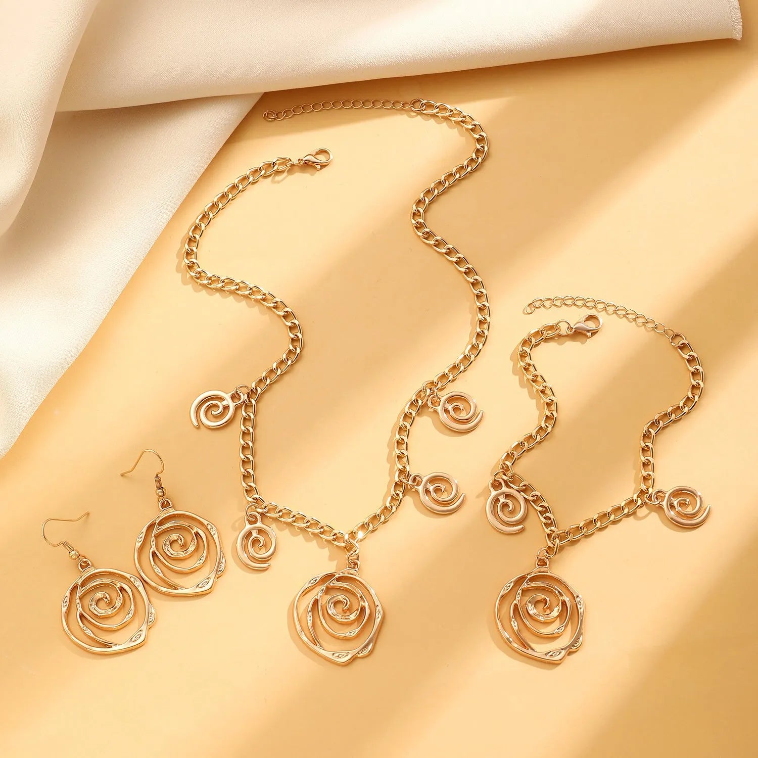 Gold spiral donut jewellery set showing necklace, bracelet and earrings with geometric circle design