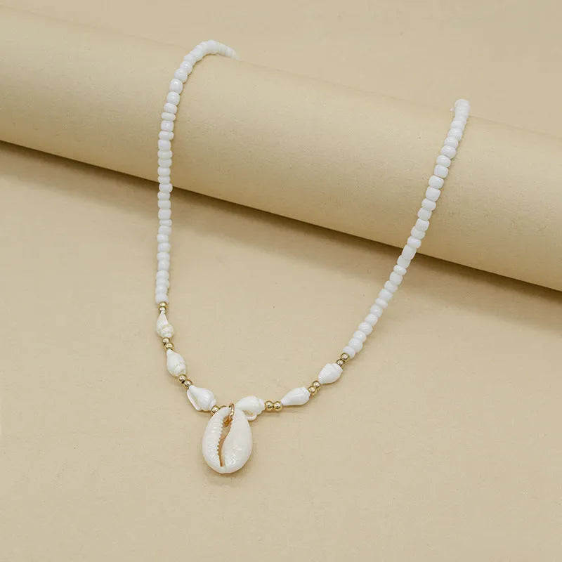 White bead necklace with conch-shaped mother of pearl shellfish pendant and regular chain