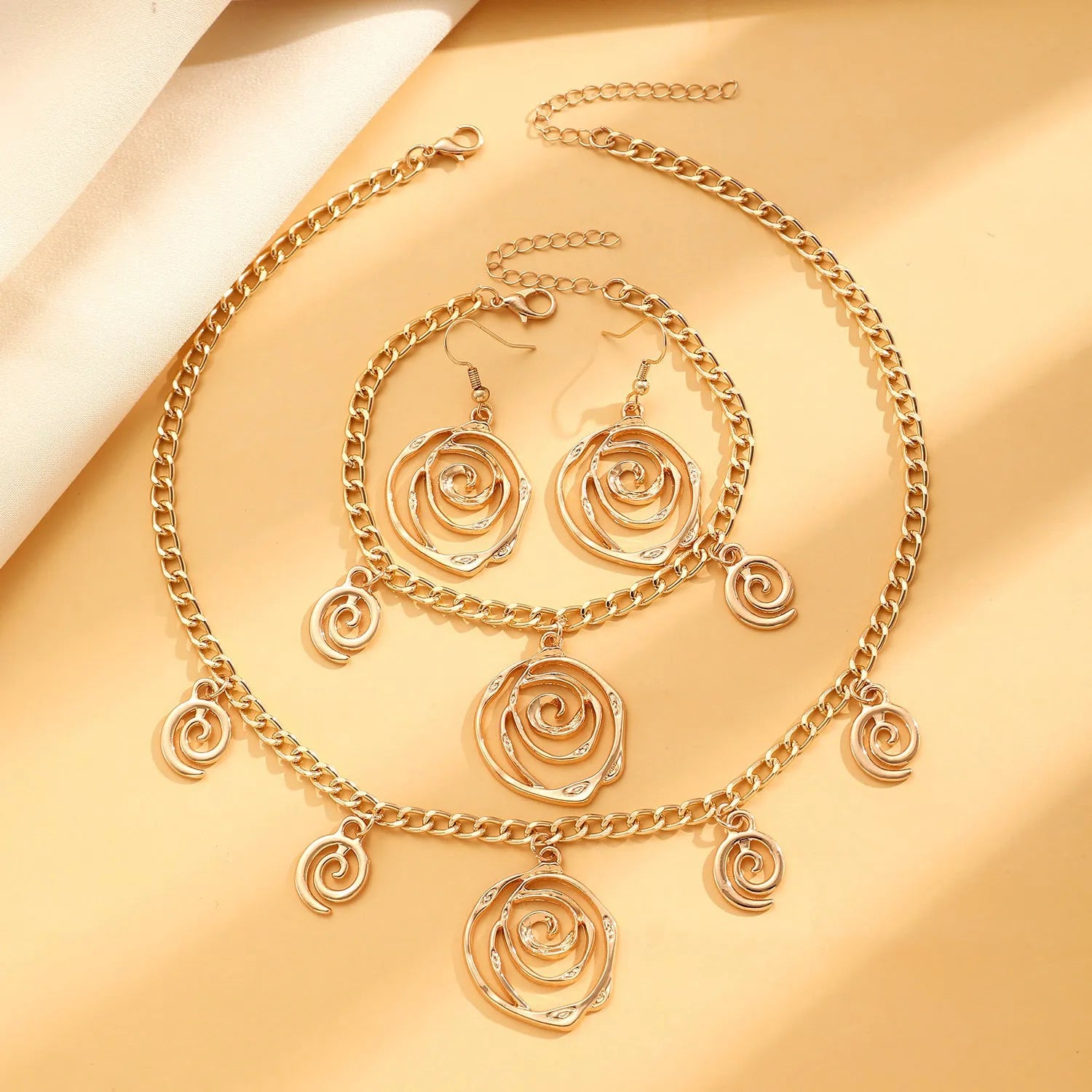 Gold spiral donut jewellery set showing necklace, bracelet and earrings with geometric circle design