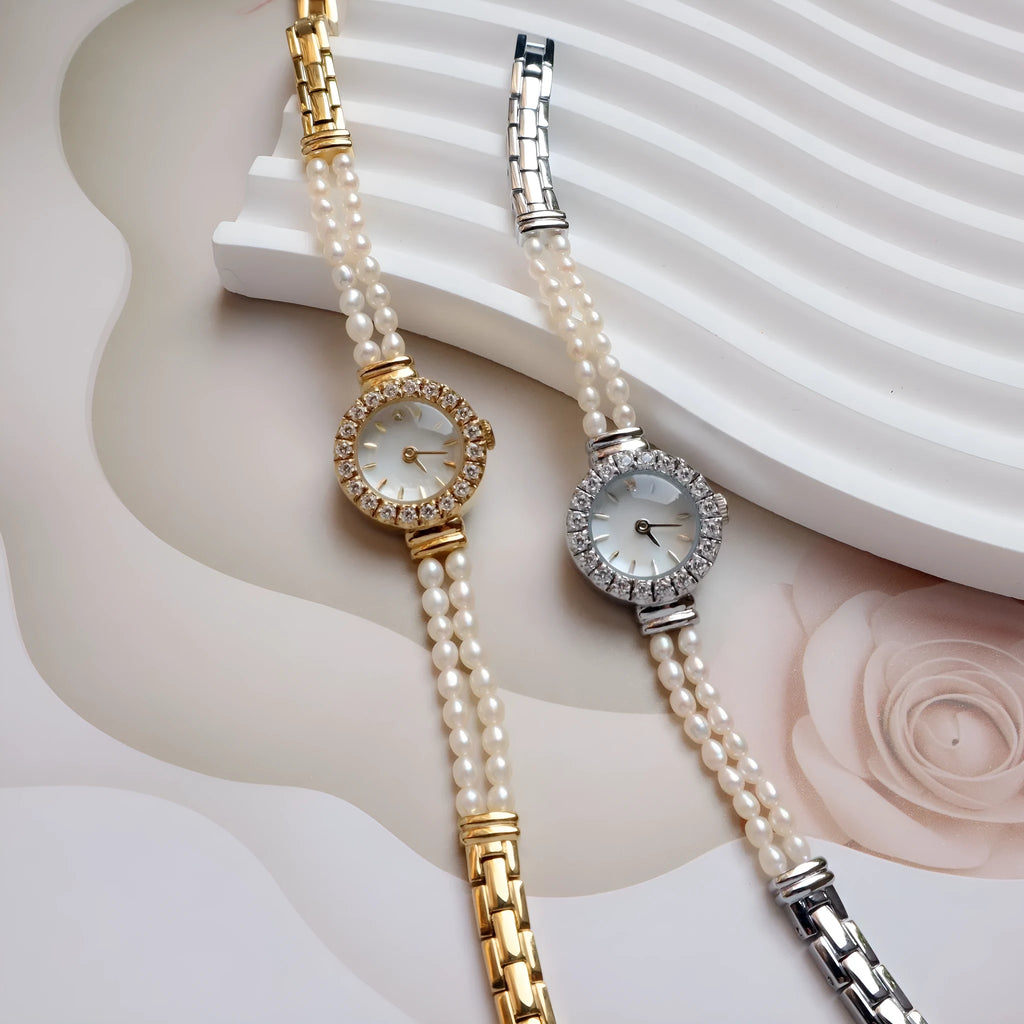 Women's light gold bracelet watch with freshwater pearls and a round 18mm dial on a stainless steel strap.
