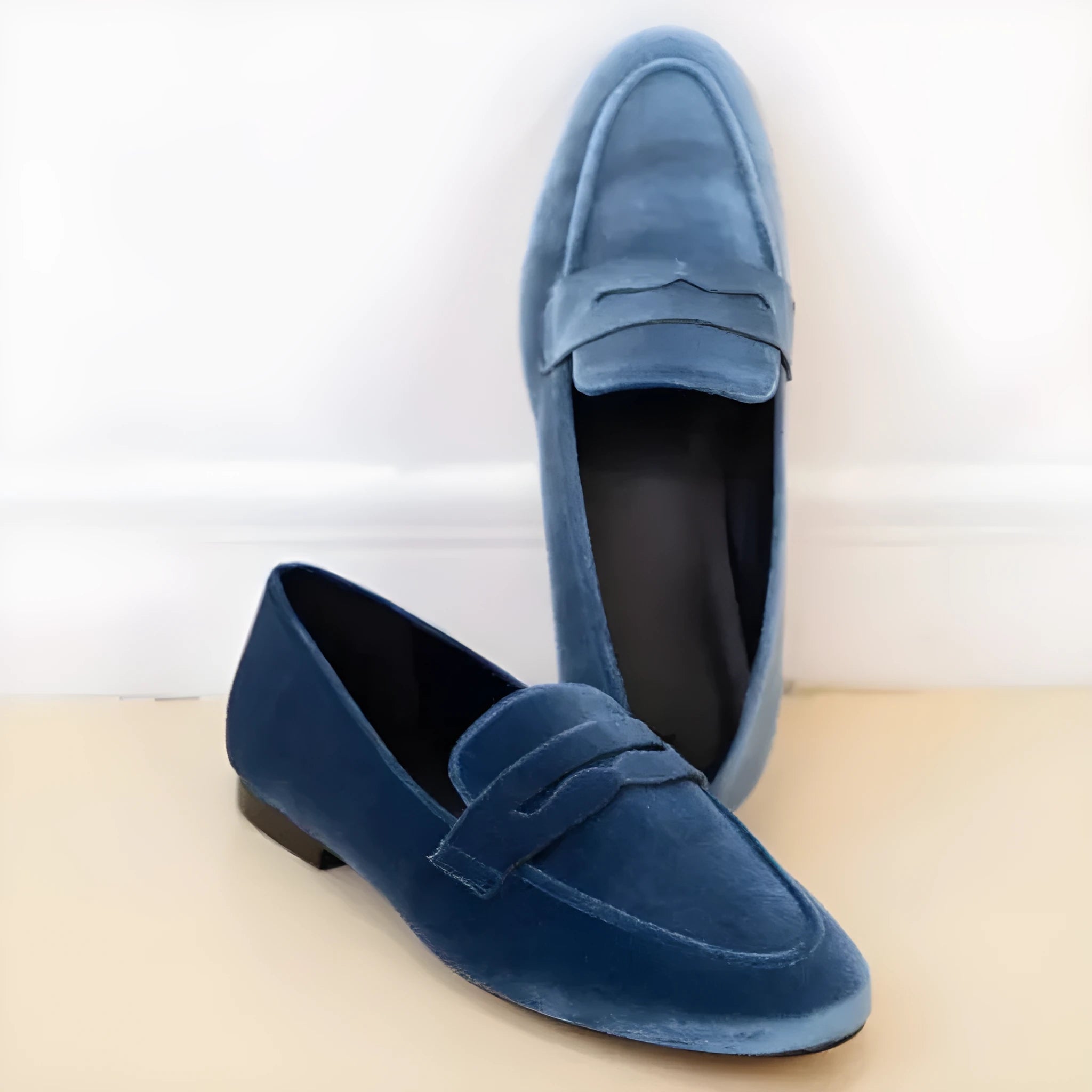Blue and black flat suede loafers with a round toe and low top on a rubber sole.